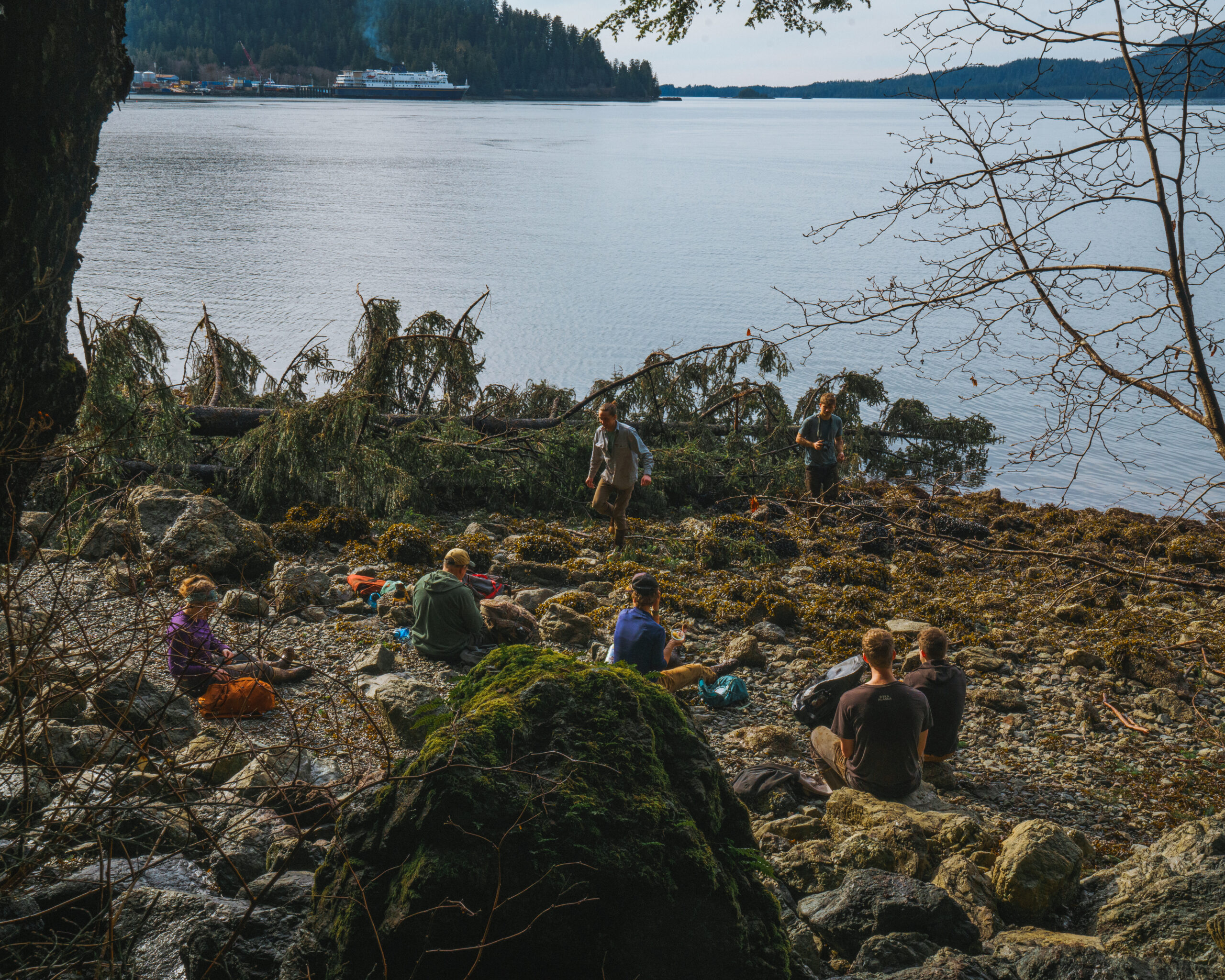 Trail Works Volunteers sit in a circle on the beach at Mosquito Cove.